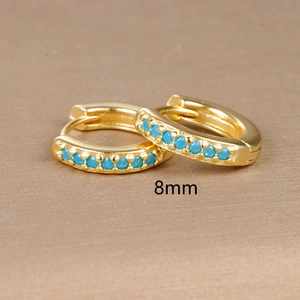 Macro shot of 8mm gold hoop earrings with blue cubic zirconia stones in a row
