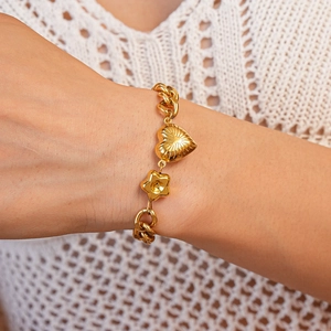 Golden chunky chain bracelet with radial heart and star charms on model wrist