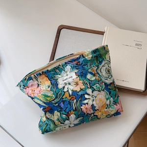 Detailed close-up of a floral cotton makeup pouch with metal zipper on a white desk