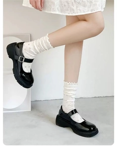 Detail of black patent leather Mary Jane shoes with thick platform and metal buckles