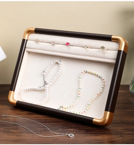 Detail of walnut jewelry tray with gold metal frame and beige velvet ring slots