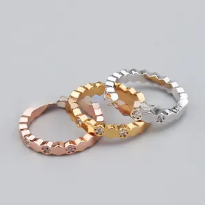 Detail of stacked hexagonal rings in rose gold, gold, and silver with zircon inlays