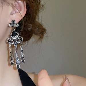 Close-up of vintage silver tassel earrings with black gemstones and intricate filigree