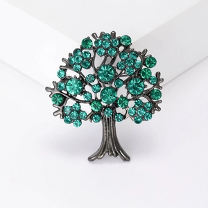 Elegant bronze tree of life brooch with sparkling green crystals on a white background