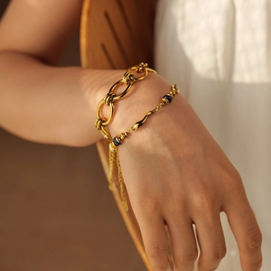 Detail of 18k gold plated double-layer chain bracelet with blue beads on model's wrist