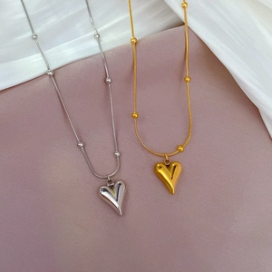 Detailed view of gold and silver heart necklaces with bead chains on silk fabric