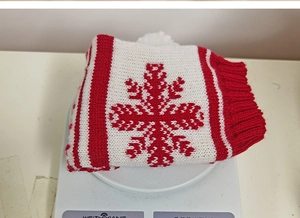 Close-up of red and white knit wine bottle cover with snowflake pattern on scale