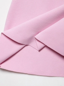 Gros plan détaillé sur la maille rose et l'élégant ourlet plissé de la jupe en tricot