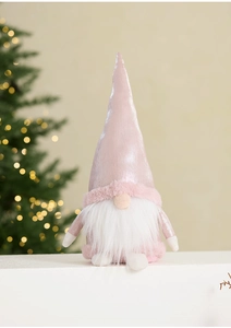 Close-up of a pink plush Christmas gnome with a long white beard and festive lighting