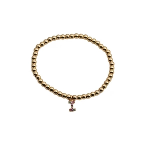 Macro detail of gold beaded bracelet with a colorful zircon-inlaid letter I pendant