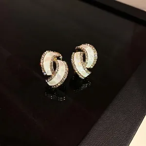 Elegante gedrehte Goldohrringe mit Perlmutt-Inlay und funkelndem Kristallrand-Design