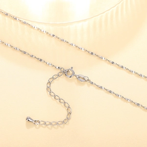 Macro detail of silver necklace chain with lobster clasp extension and teardrop charm