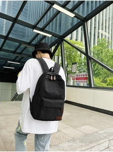 Rear view of minimalist black canvas backpack with large main compartment and zip pocket
