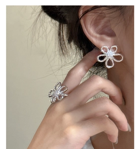 Macro detail of S925 silver flower earrings and ring set with sparkling zircon stones