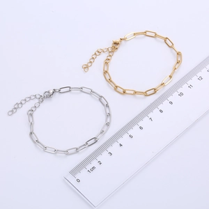 Detail view of gold and silver paperclip chain bracelets with length measurement scale