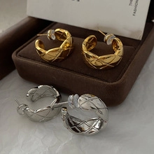 Close-up of C-shaped earrings with quilted texture in gold and silver finishes