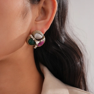 Vintage gold earrings with green and purple gemstones shown on a model side profile