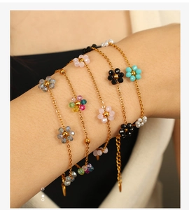 Detail of colorful crystal flower beaded bracelets layered on a model's wrist with gold chain
