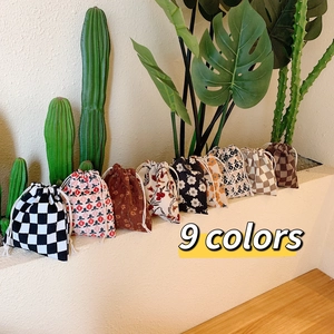 Nine colorful cotton drawstring pouches with floral and checkered patterns for organizing