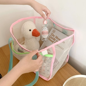 Large mesh beach tote bag in beige with pink trim and green handles for storage