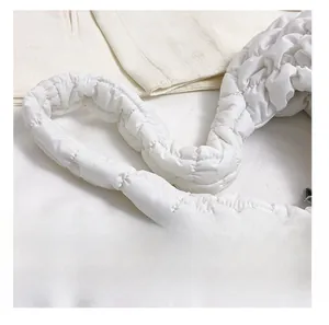 Close-up of a white quilted padded strap on a cloud bag with soft nylon texture