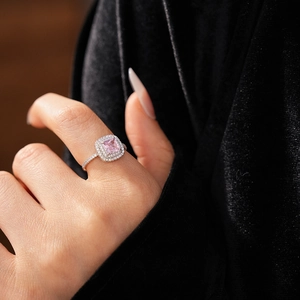 Macro shot of princess cut pink zircon ring with halo setting on black velvet