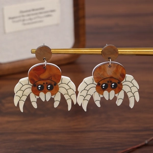 Brown acrylic spider earrings with amber texture hanging on a gold metal stand for Halloween