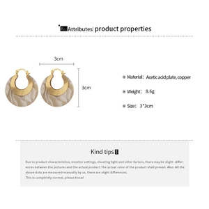 Detail view of round acetate earrings with beige marble pattern and golden copper trim
