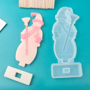 Detailed view of snowman-shaped silicone mold with finished resin craft on blue background