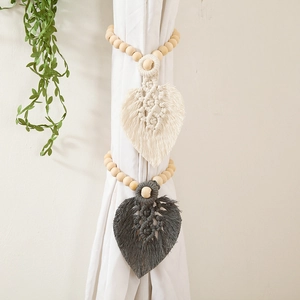 Detail of leaf-shaped cotton woven curtain tiebacks with wood beads in beige and grey