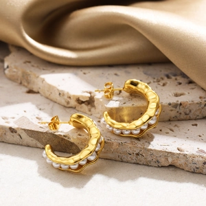 Élégantes boucles d'oreilles créoles C en or 18 carats avec perles sur fond texturé