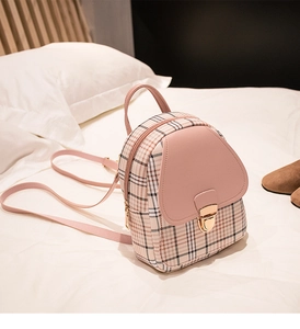 Detailed view of pink plaid PU leather mini backpack with golden metal lock on bed