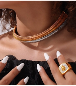 Close-up of triple-layered industrial gold necklace and geometric chunky signet ring