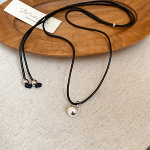 Close-up of polished silver sphere pendant with adjustable black cord necklace