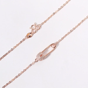 Detail of rose gold safety pin pendant with micro-pave zircons and S-clasp chain