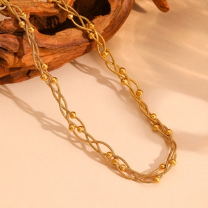 Gros plan du collier serpent doré multicouche avec perles sur bois vieilli