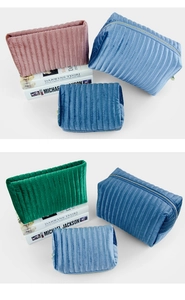 Close-up of ribbed velvet makeup bags in pink, green, and blue with metal zippers