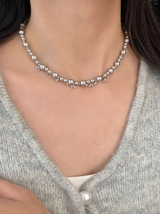 Macro view of grey pearl necklace with flower-shaped diamond-set metal accents on neck