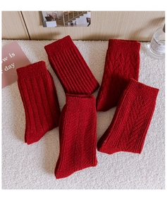 Close-up of assorted red thermal knit socks with various textures on white faux fur