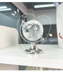 Detailed view of a mini crystal globe with a silver metal base and internal map texture