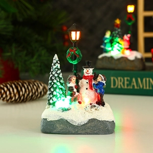 Close-up of a Christmas snowman miniature scene with glowing LED street lamp and resin details