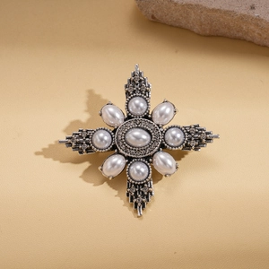 Macro view of vintage silver brooch with faux pearl center and rhinestone starburst details