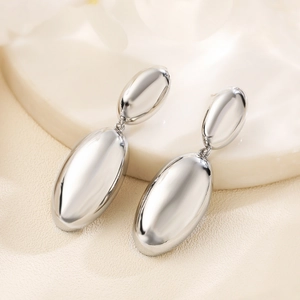 Polished silver geometric teardrop earrings with smooth metallic finish on beige texture