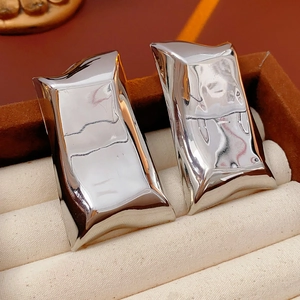 Gros plan de boucles d'oreilles carrées irrégulières en argent dans une boîte en velours