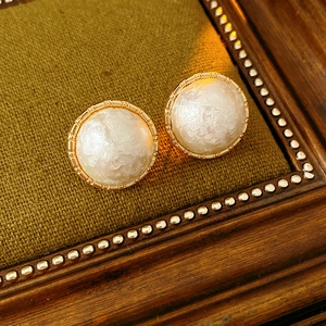 Close-up of vintage gold plated round pearl stud earrings on a green velvet backdrop