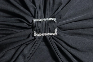 Detail of black pleated fabric featuring a luxury rhinestone rectangular buckle embellishment