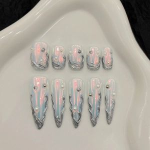 Silver aurora press-on nails with 3D flame patterns and pearls on ceramic tray