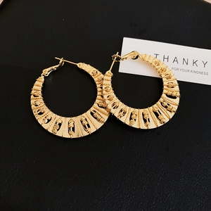 Detail of large gold twisted hoop earrings with intricate hollow woven texture