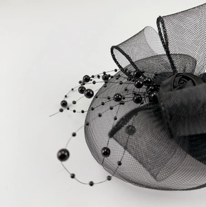 Detail of black fascinator hat with elegant mesh veil and pearl bead embellishments