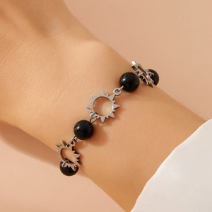 Stainless steel sun charm bracelet with faux pearls and black beads on a model wrist